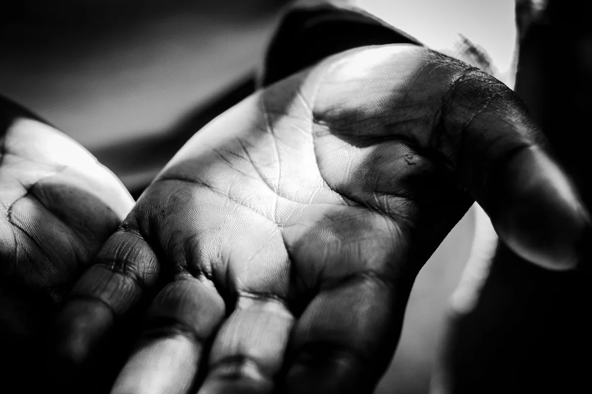 A hand in hard directional light against darkness.