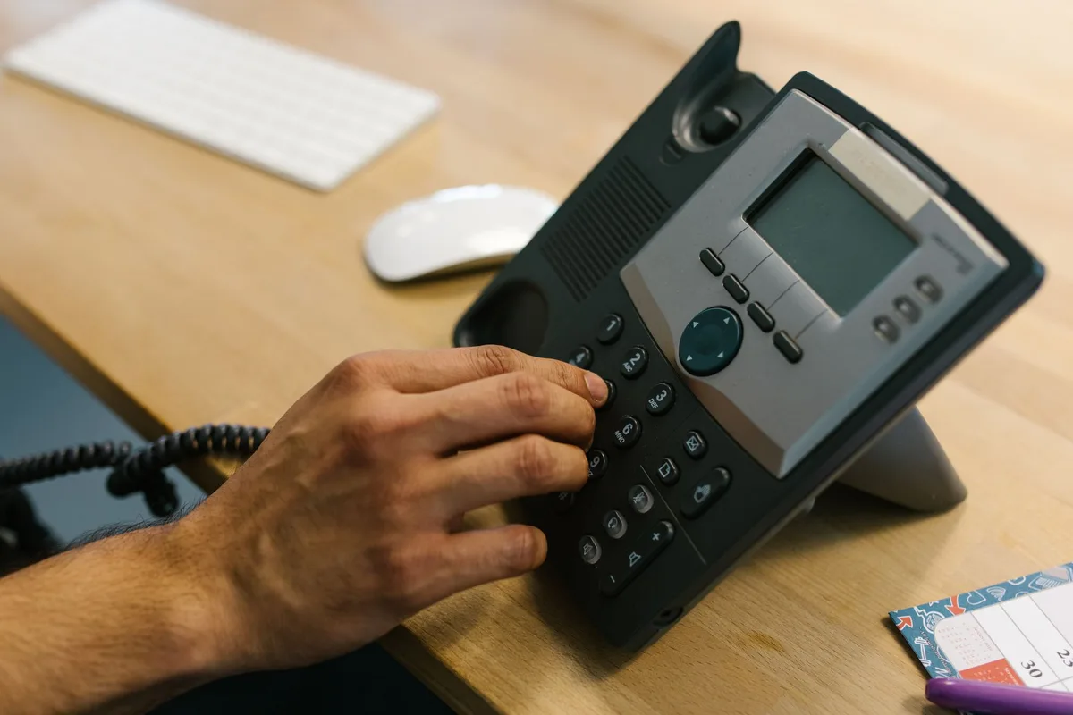 A telephone handset on a dark desk under hard directional light.