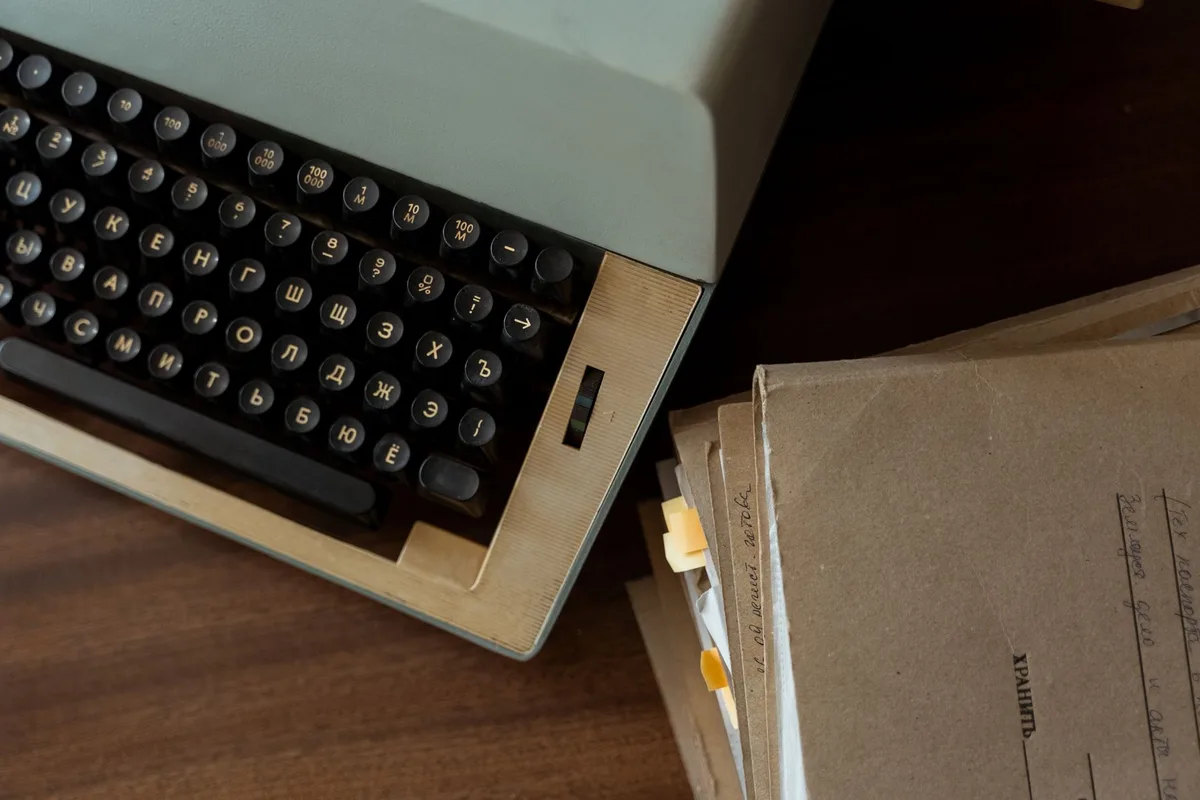 A stack of paperwork on a dark desk under hard directional light.