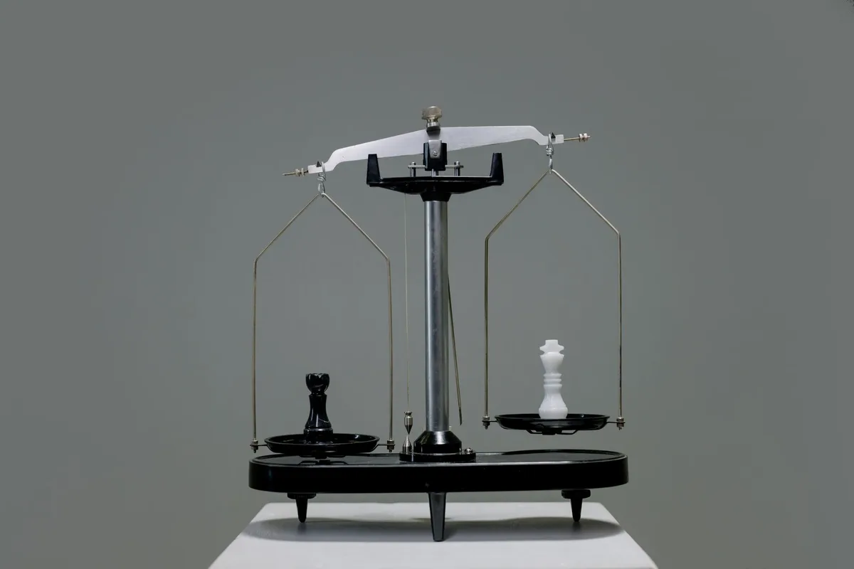 A set of balance scales on black, lit hard from one side.