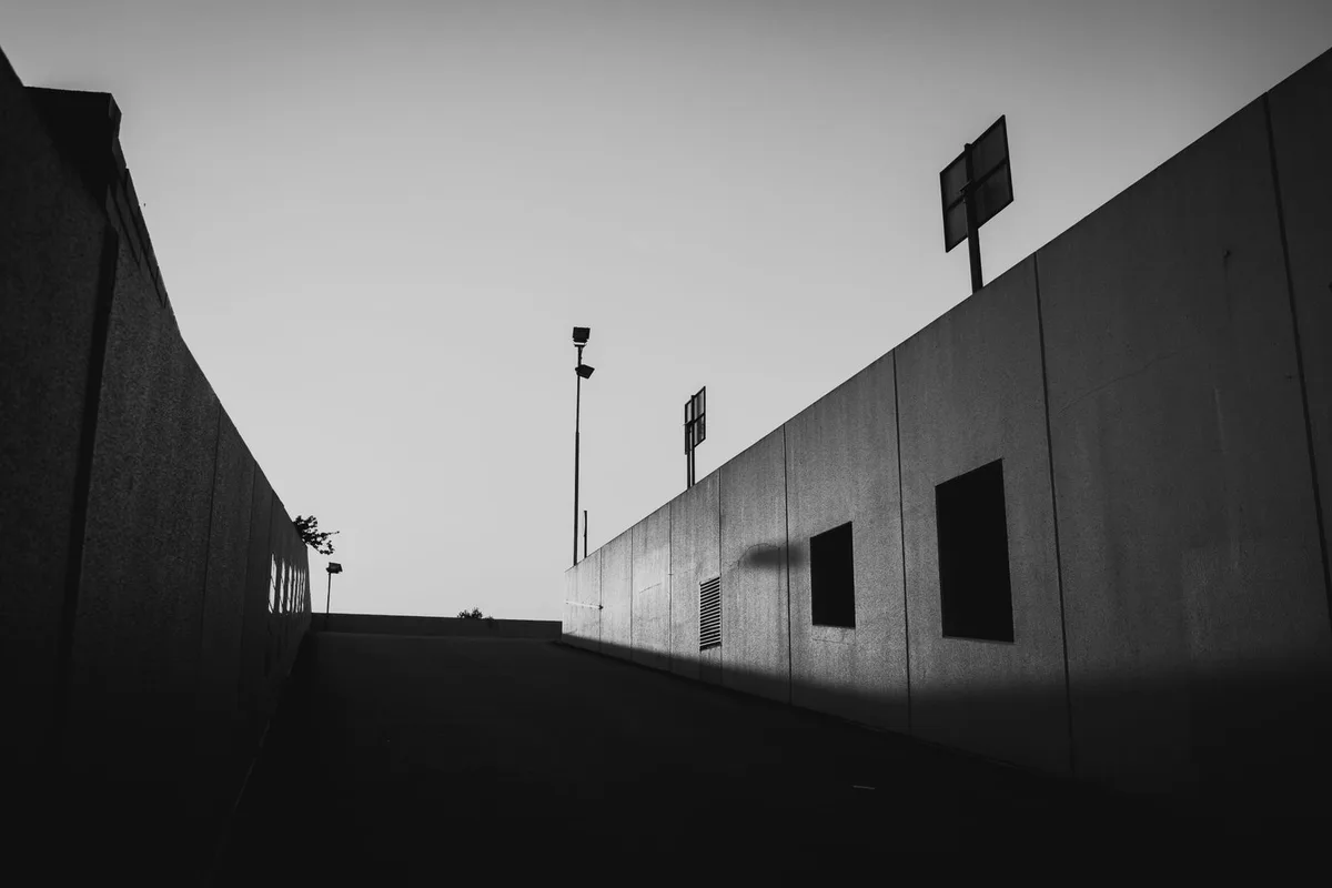 A road at dusk under street lights, photographed in hard monochrome.