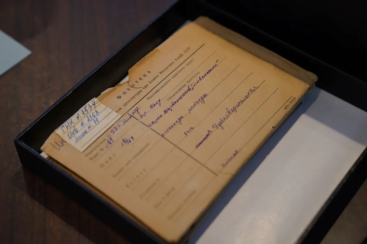 Archive folders and handwritten notes on a dark surface under directional light.
